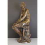 A patinated bronze figure of a seated nude,