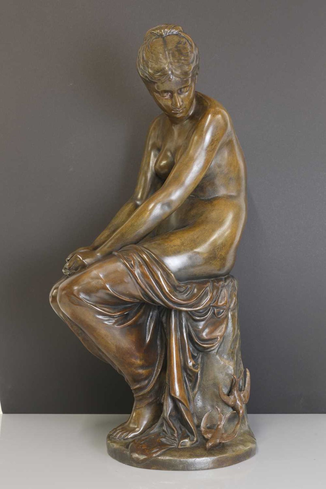 A patinated bronze figure of a seated nude,