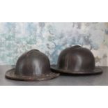 A pair of patinated leather miner's helmets,