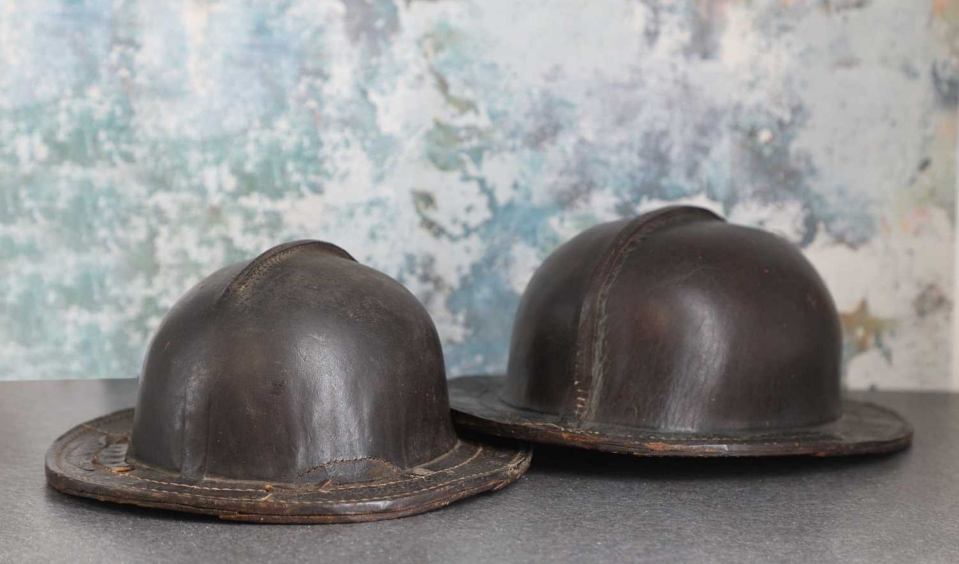 A pair of patinated leather miner's helmets,