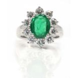 An 18ct white gold Zambian emerald and diamond oval cluster ring,