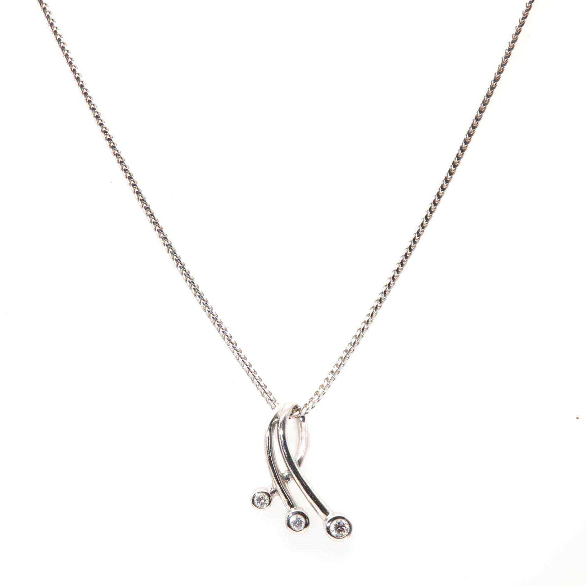 An 18ct white gold three stone diamond spray pendant,