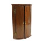 A George III oak and mahogany bow front corner cupboard