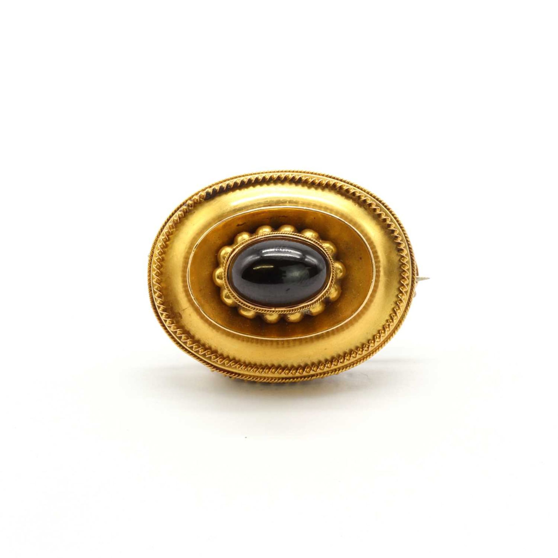 A Victorian gold and garnet oval shield brooch,