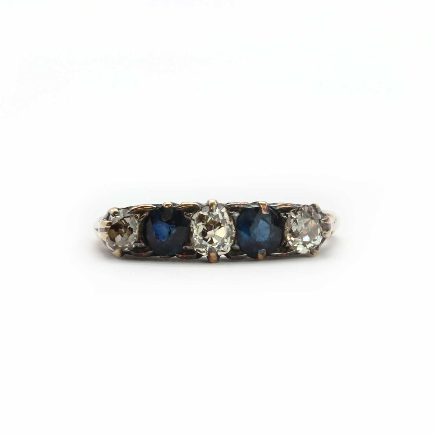 A gold diamond and sapphire five stone carved head ring,