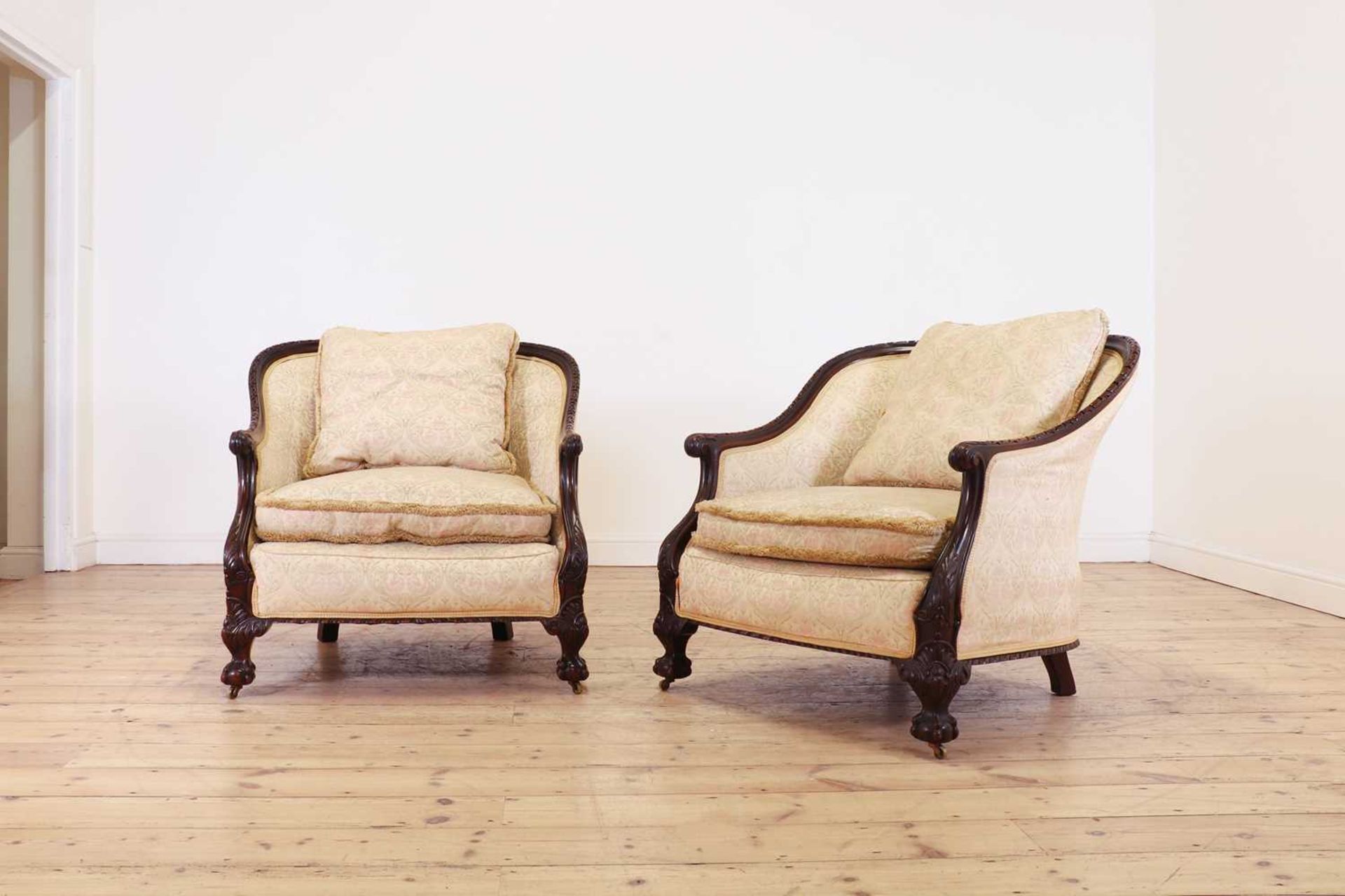 A pair of large carved mahogany low bergère chairs,