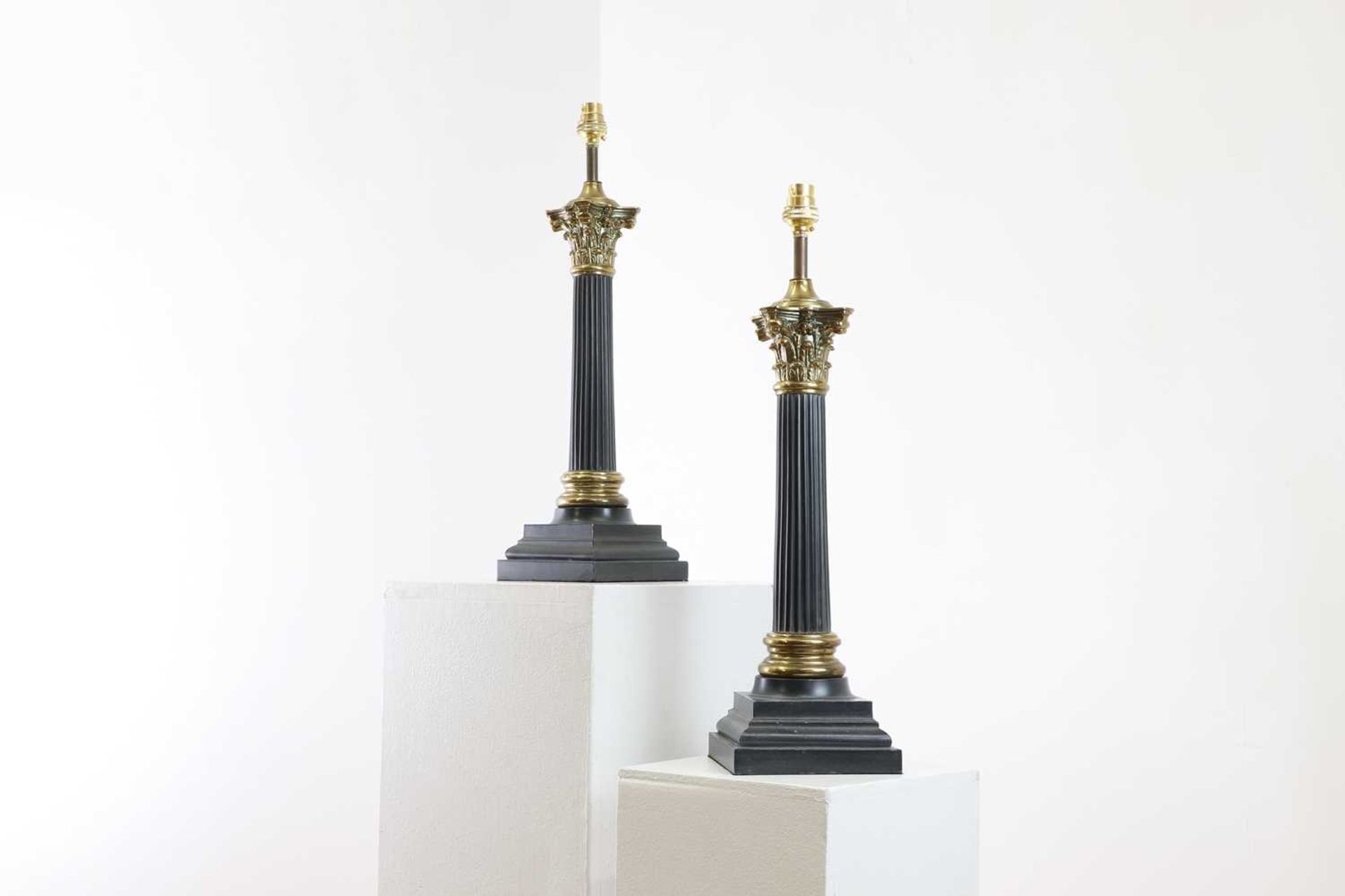 A pair of patinated and gilt-metal column table lamps