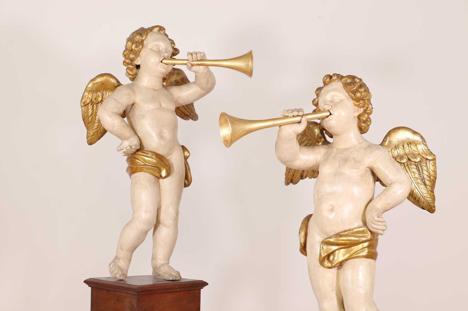 A pair of painted and parcel-gilt wooden putti,