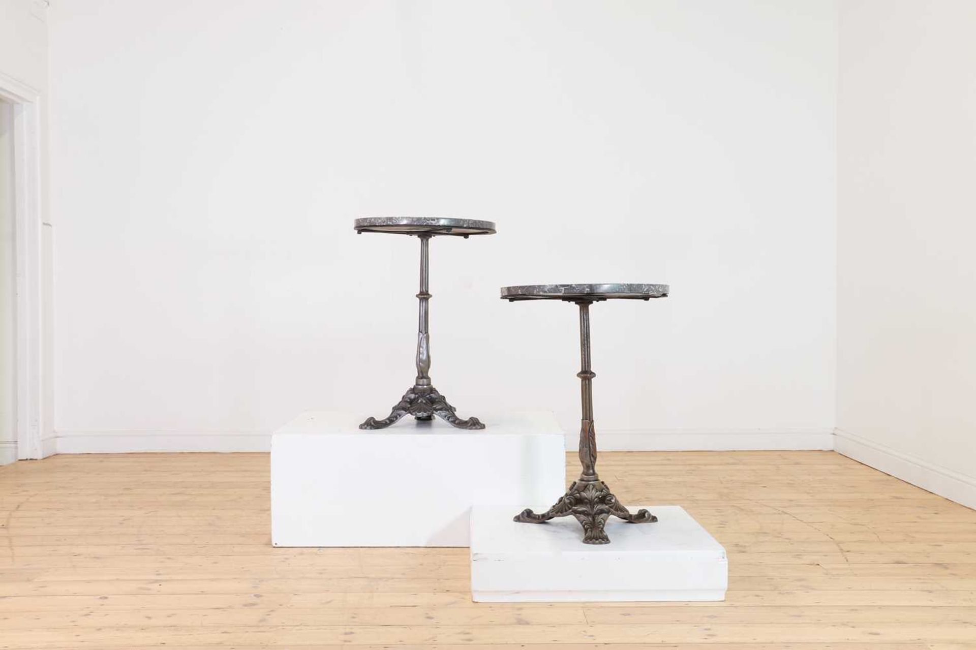 A pair of marble and polished cast iron bistro tables,