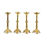 A group of four brass ecclesiastical style candlesticks