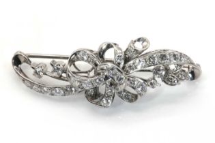 A diamond set scrolling ribbon brooch, c.1950,