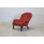 An upholstered chair on turned front legs and castors,