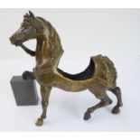 A bronze sculpture of a horse with decorative cast harness and open saddle section (saddle, leg