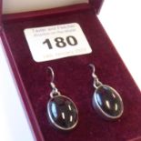 A pair of lady's silver-mounted drop earrings: each set with a dark red oval stone polished en
