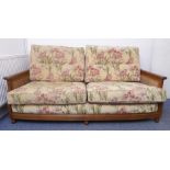 A good Ercol two-seater sofa; rich coloured elm and rattan-caned sides; upholstered lily pattern