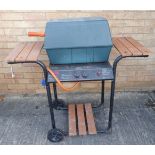 A Thermos gas barbeque; the hinged lid lifting to reveal grilles flanked by slatted shelves (105