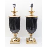 A pair of urn-shaped table lamps with fluted black verticals and circular spreading feet onto plinth