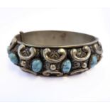 An Italian white metal bangle: the outer edge decorated with ten vertical oval turquoise stones