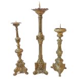 Three continental brass pricket candlesticks: one of Gothic triform with architectural elements; and