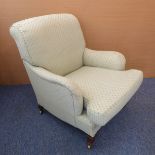 An early 20th century upholstered armchair raised on square tapering front legs with castors: each