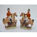 An opposing pair of 19th century Staffordshire models of mounted huntsmen, each holding a hare (18.