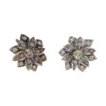 A pair of diamond ear clips, each modelled as a flowerhead and centrally-set with an old brilliant-