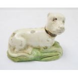 A late 18th to early 19th century Pearlware model of a recumbent hound wearing a collar (11 cm