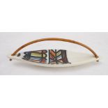 A circa 1950s kayak-shaped Vallauris dish: bowed bamboo handle above a brightly decorated abstract