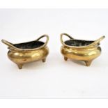 A pair of polished brass/bronze, two-handled tripod censers in 17th century style: each with