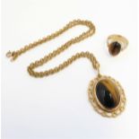 An oval tiger's eye cabochon pendant and ring: the pendant within a collet and openwork border,