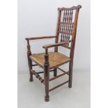 An early 19th century ash vernacular open armchair: shaped top rail above spindle turned back,