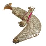 A cased Omani khanjar: shaped horn handle and white metal mounted with ornate scrolling and other