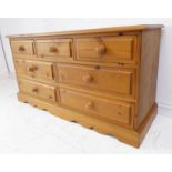 A modern long and low pine chest: moulded top; three top frieze drawers and four half-width