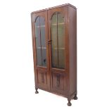 An early 20th century display cabinet: two glazed doors enclosing shelves and with decorative panels