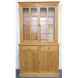 A modern light oak display cabinet; cavetto style cornice above two glazed doors with moulded