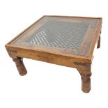 An Eastern-style hardwood coffee table with an iron wire mesh centre, raised on turned tapering legs