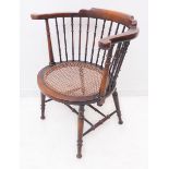 An early 20th century captain's-style chair: slender turned uprights above a circular rattan-caned