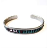 A silver bangle: the front enamelled section decorated with geometric style shapes and the sides