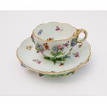A late 19th century Meissen teacup and saucer: the teacup with applied flowers (some extremities