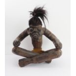 A large carved tribal figure: seated male, open armed and with irate expression (47 cm wide x 48