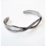 A stylish silver bangle as intertwined, half-tube designs (boxed)