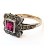An Art Deco style silver ring with twelve small diamonds surrounding a central square cut stone (