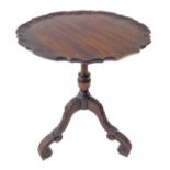 A Georgian-style mahogany wine table: piecrust top above turned stem and three downswept legs carved
