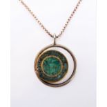 A circular silver pendant with central section comprised of malachite and turquoise re-constituted