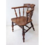 A 19th century elm smoker's bow armchair: large shaped seat and turned slightly splaying ebonised