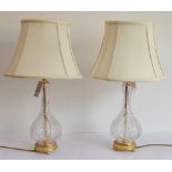 A pair of globe and shaft style clear glass and gilt metal mounted table lamps with matching shades: