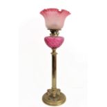 A 19th century brass and cranberry glass oil lamp: the crimped edge shade above a cranberry glass