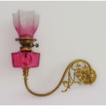 A 19th century wall-mounted brass and cranberry glass oil lamp: the six-pointed etched shade above a