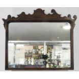 A walnut-framed looking-glass in 18th century style (reproduction) and with shaped pediment (65.5 cm