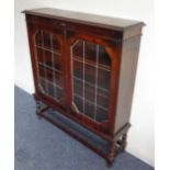 An early 20th century oak display cabinet: the moulded top above split turned mouldings to the